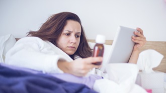 mulher na cama doente a aceder a serviços de saúde no tablet