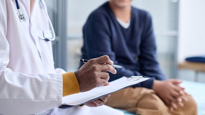 Pessoa em consulta médica, sentada numa marquesa