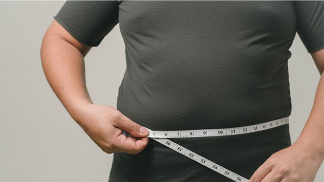 Homem a medir perímetro abdominal com fita métrica