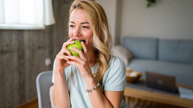 mulher a comer uma maça verde