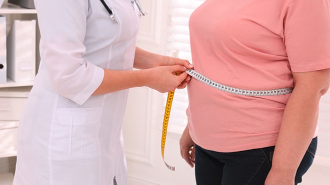 Plano médio de enfermeira a medir a cintura a uma pessoa com excesso de peso