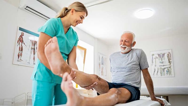 Fisioterapeuta a dobrar perna de paciente