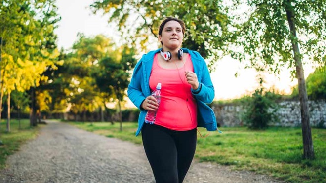 Mulher com excesso de peso corre num jardim