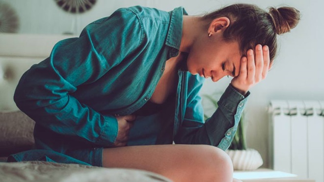 Mulher adulta com dores na zona pélvica, dobrada sobre si