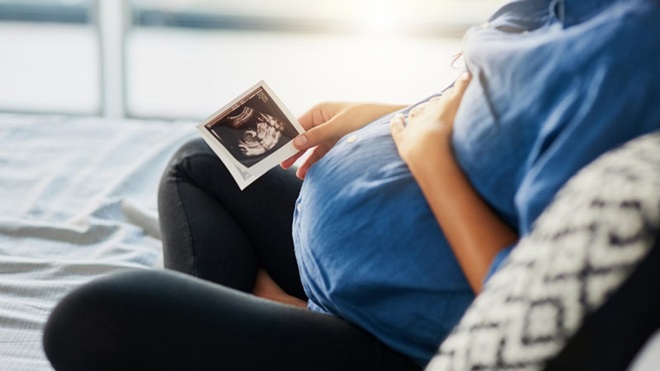 mulher grávida com fotografia na mão