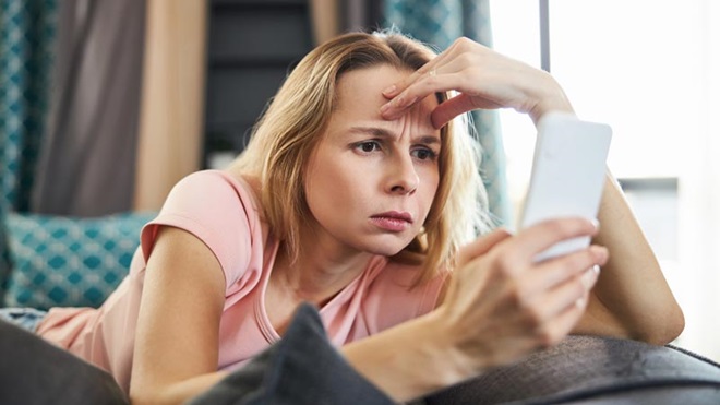 jovem deitada na cama a olhar para o telemóvel