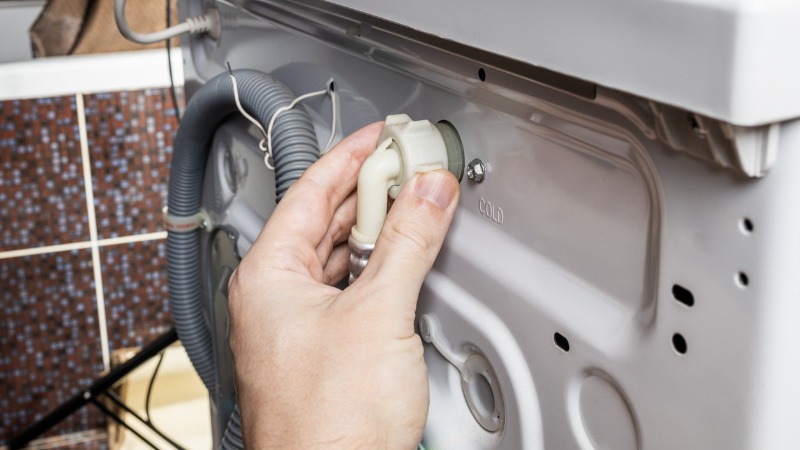 Consumidor verifica se máquina de lavar roupa está corretamente ligada.