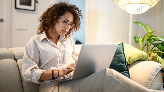 mulher sentada no sofá com o portatil