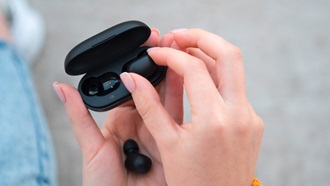 Grande plano de mãos femininas a retirar auriculares sem fios da sua bolsa