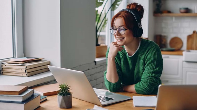 Mulher a trabalhar ao computador com auscultadores almofadados