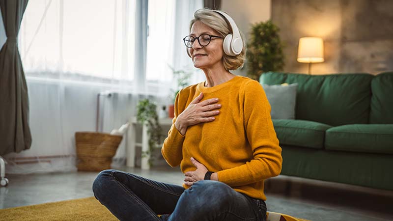 Mulher adulta com auriculares, sentada no chão da sala