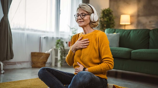 Mulher adulta com auriculares, sentada no chão da sala