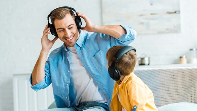Pai e filho sentados no sofá com auscultadores