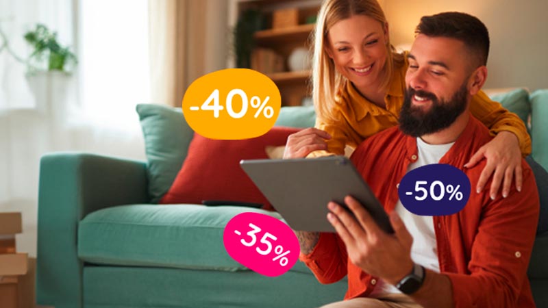 Casal sentado num sofá numa sala com três balões de percentagens por cima: -40%, -35% e -50%