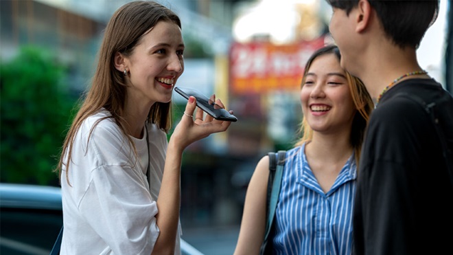 Três pessoas a conversar, uma delas a usar o telemóvel para traduzir a conversa