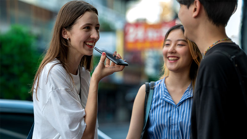 Três pessoas a conversar, uma delas a usar o telemóvel para traduzir a conversa