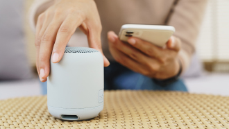 Mulher a conectar telemóvel a coluna bluetooth.