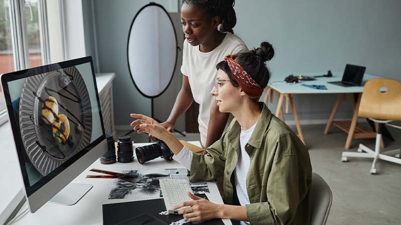 Duas mulheres a fazer edição de imagem em escritório de design