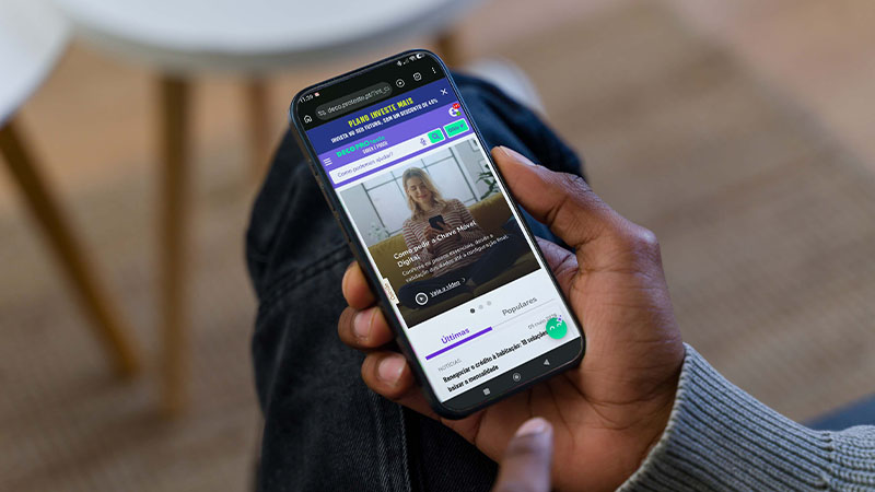 Pessoa a segurar telemóvel com browser aberto na homepage da DECO PROteste
