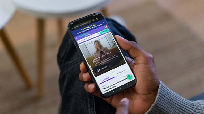 Pessoa a segurar telemóvel com browser aberto na homepage da DECO PROteste