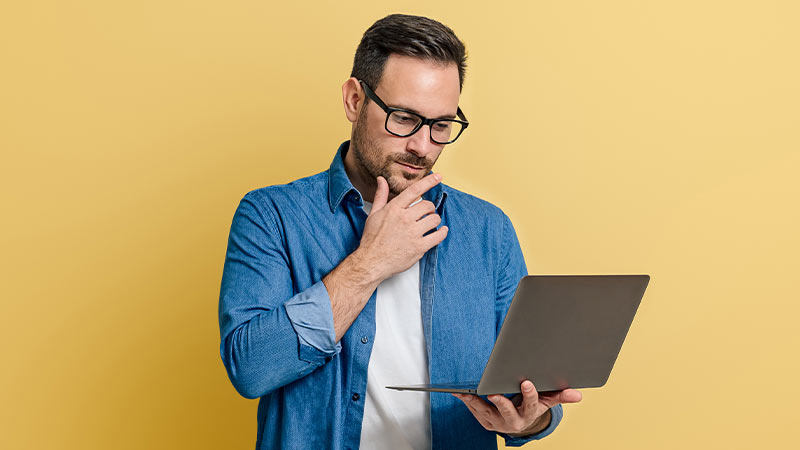 Homem preocupado a olhar para o seu portátil, fundo amarelo
