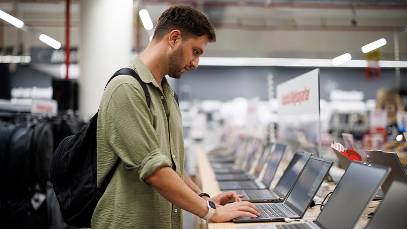 Homem a escolher um portátil numa loja de eletrodomésticos