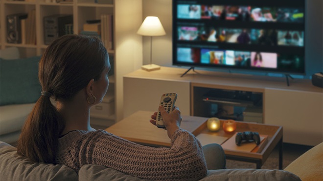 Mulher a ver televisão numa sala escurecida