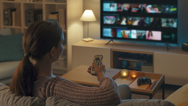 Mulher a ver televisão numa sala escurecida