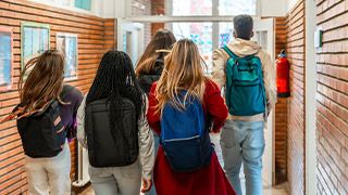 jovens de costas com mochilas num corredor de uma escola