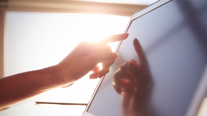Ecrã de computador portátil em grande plano, uma pessoa toca com o dedo polegar no ecrã.