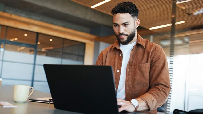 Homem num portátil, no escritório