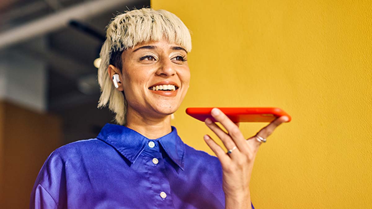 Mulher moderna a falar para um telemóvel - alusão a tradução com AI
