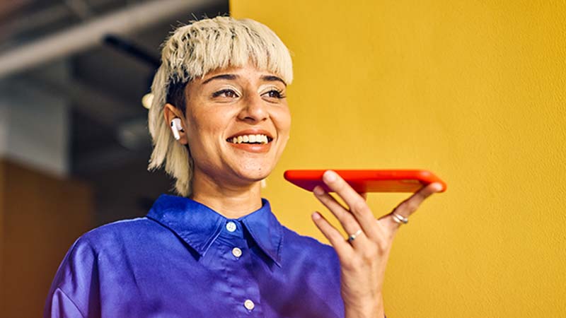 Mulher moderna a falar para um telemóvel - alusão a tradução com AI