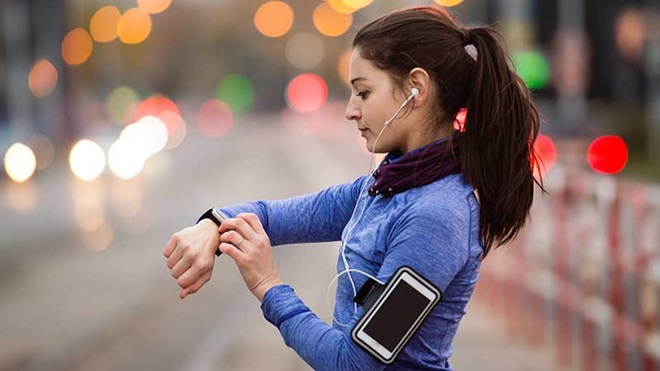 Mulher com roupa de desporto a verificar app de exercício no smartwatch.