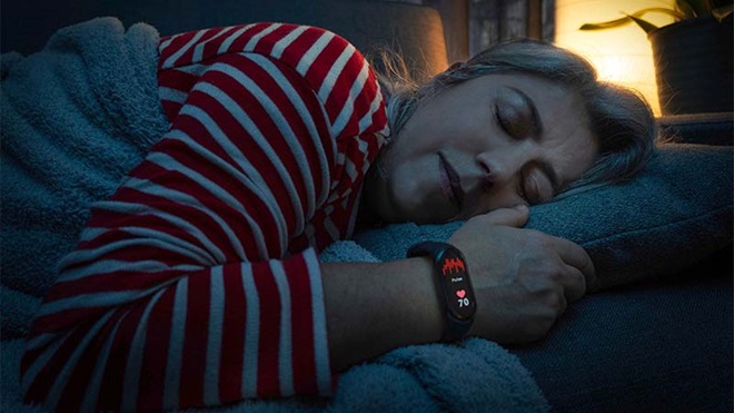 Mulher de meia idadea dormir usando pulseira de fitness