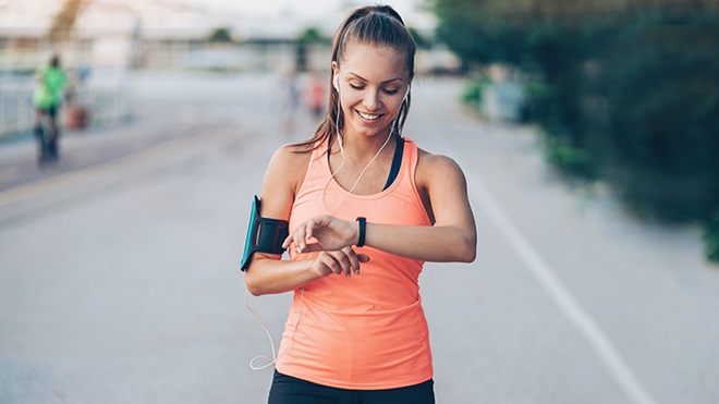 Rapariga a caminha e a olhar para pulseira de fitness
