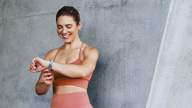 Mulher jovem com roupa de desporto consulta a pulseira desportiva