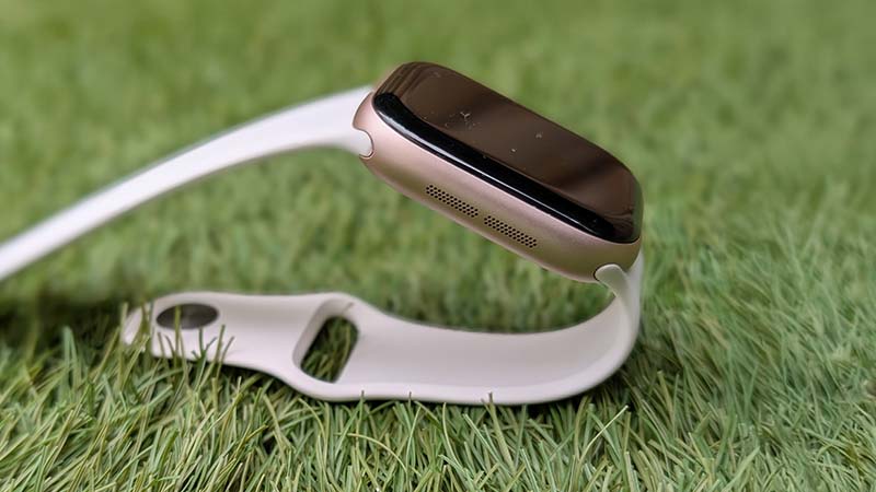 Smartwatch Apple Watch 11 series branco e dourado sobre relva