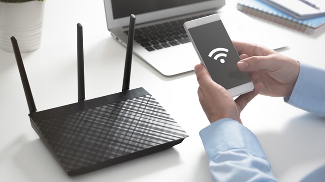 extensor de rede wi-fi com ligação ao telemóvel e ao computador portátil em cima de uma mesa