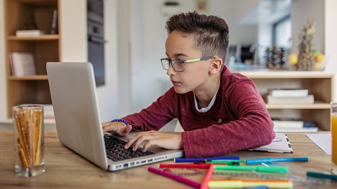 Criança a estudar em casa num computador portátil