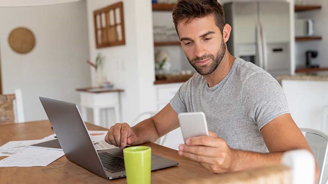 Homem com portátil e smartphone