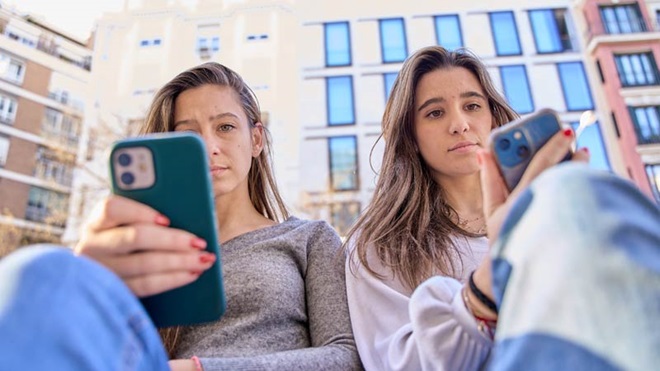 Duas raparigas com o telemóvel na mão