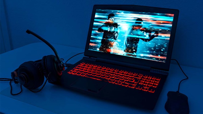 Portátil com mouse e phones para jogos em cima de uma mesa com fundo azul escuro e ecrã a mostrar um jogo de guerra