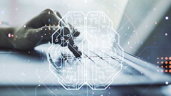 Uma mão a tocar no teclado de um computador portátil, com a imagem gráfica de um cérebro em marca de água sobre a fotografia