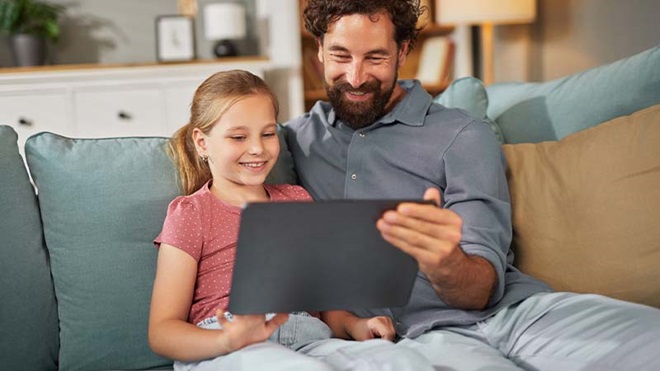 Pai e filha no sofá a ver tablet
