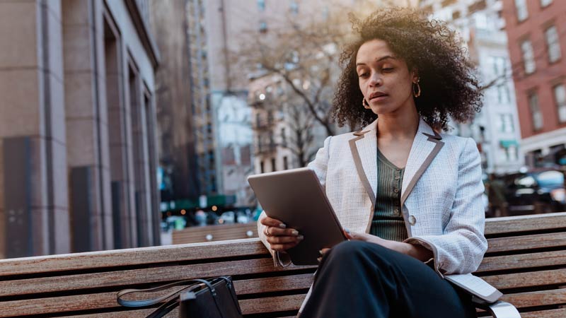 mulher sentada num banco com tablet na mão