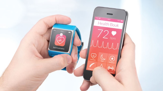 mãos masculinas seguram um telefone inteligente preto e um relógio inteligente azul, ambos com uma aplicação de saúde (ecrão com batimentos cardíacos e símbolo do coração)