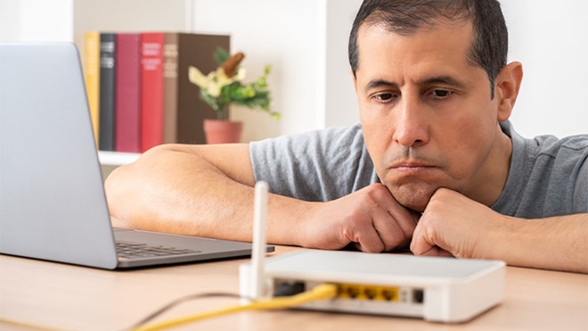 Homem a olhar para router com ar ligeiramente zangado