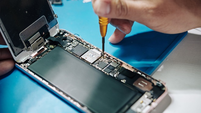 Telemóvel aberto, em bancada de trabalho, a ser reparado com chave de parafusos