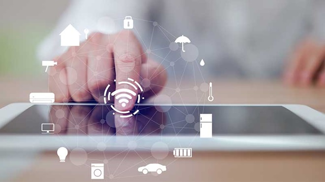 Tablet em cima de mesa de madeira e mão de utilizador a selecionar funções de aparelhos conectados